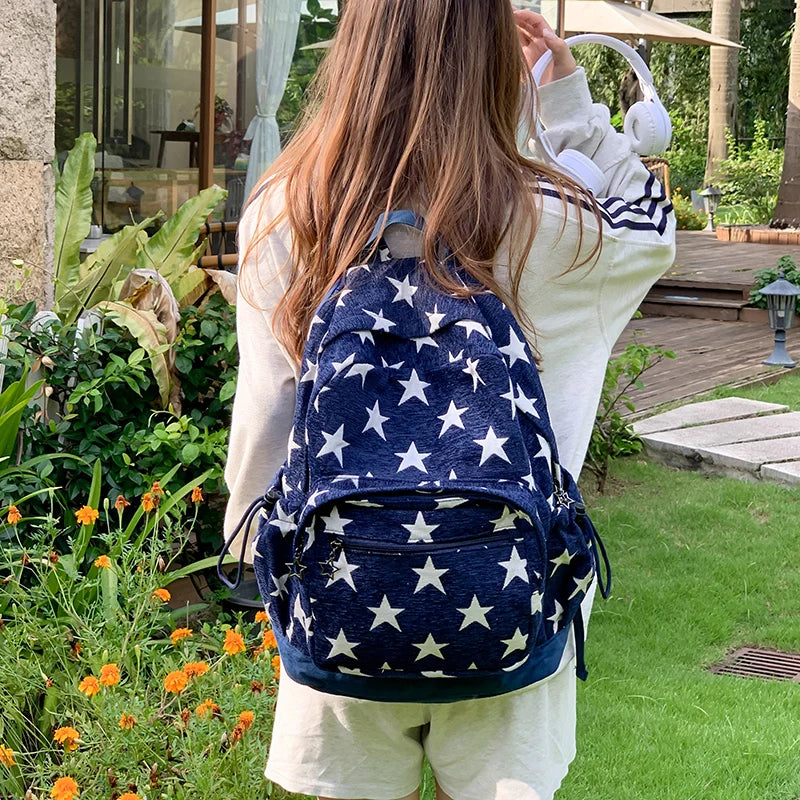 Person wearing a blue backpack with white star patterns in an outdoor setting.