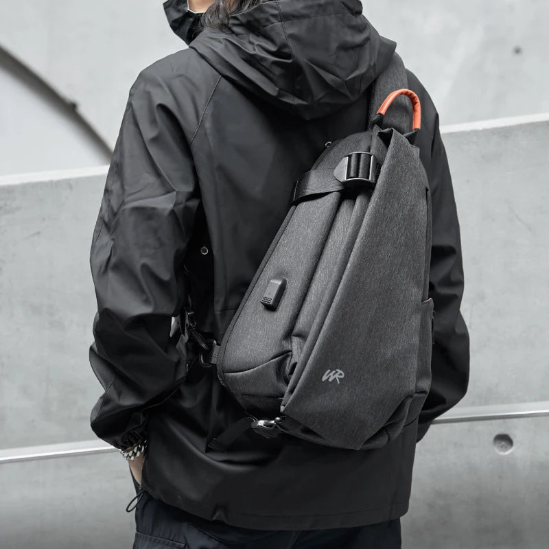 Person wearing a black jacket with a gray backpack against a gray background