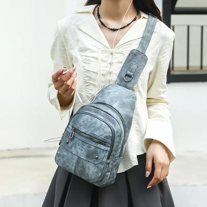 Person wearing a gray suede crossbody bag with a blurred background