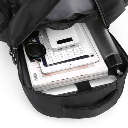 Black backpack with items including a keyboard, tablet, and power bank on a white background