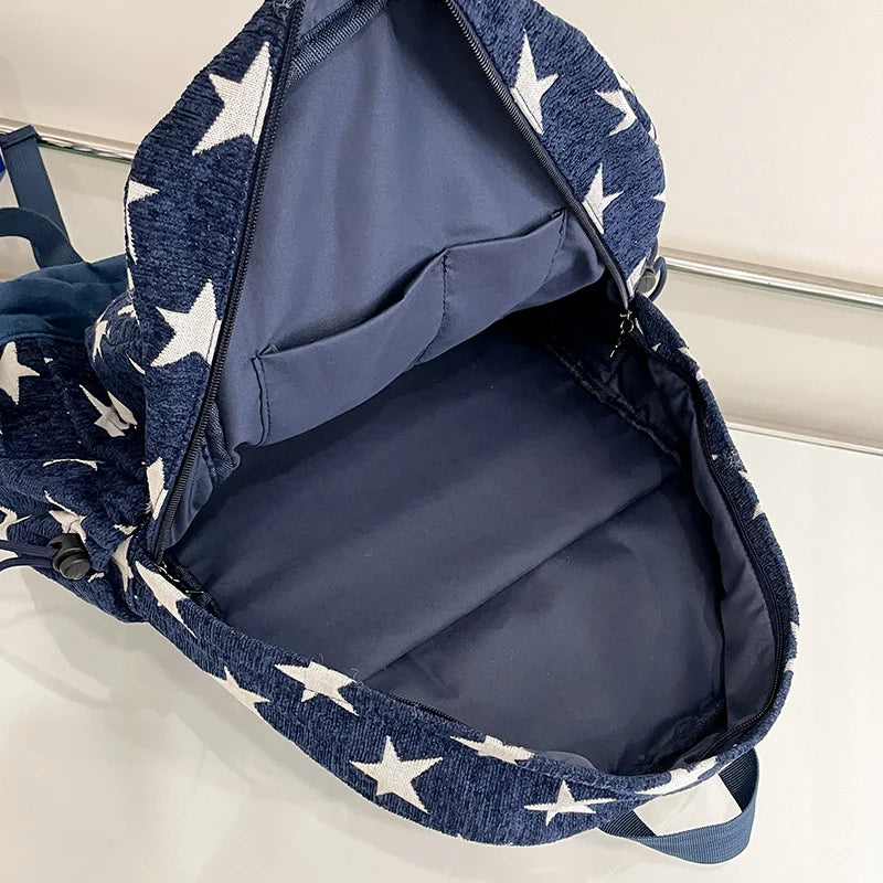 Navy blue backpack with white star pattern on a light gray background