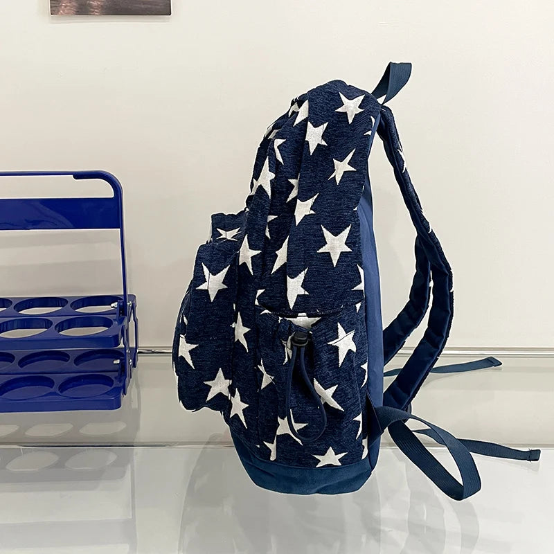 Navy blue backpack with white star pattern on a reflective surface.