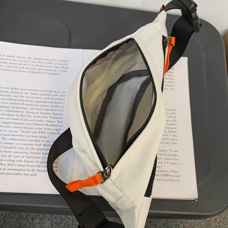 White crossbody bag with orange accents on a book