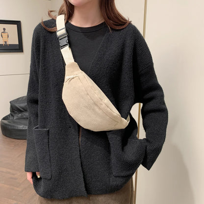 Person wearing a dark gray cardigan with a beige crossbody bag indoors.