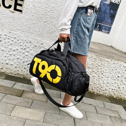 Person holding a black duffel bag with yellow 'T90' logo on a textured wall background