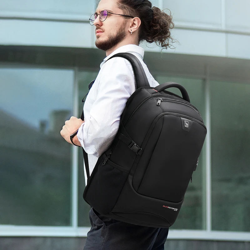 Man wearing a black backpack in front of a glass building