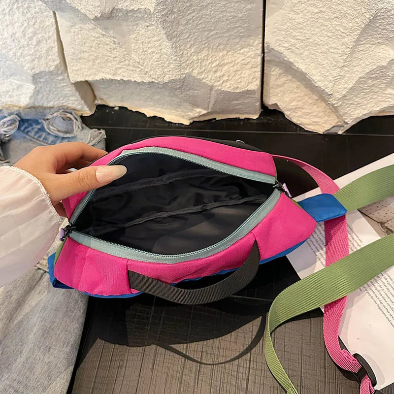 Pink bag with a green strap held by a person against a textured wall.