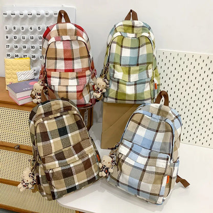 Four plaid backpacks on a white surface with a calendar in the background.