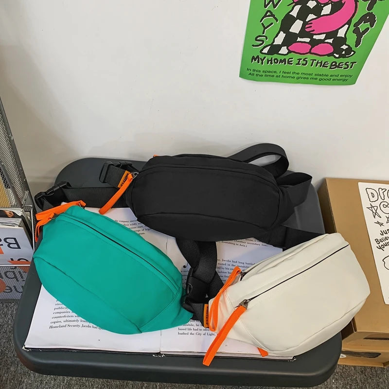 Two waist bags, one green and one beige, with orange zippers on a surface.