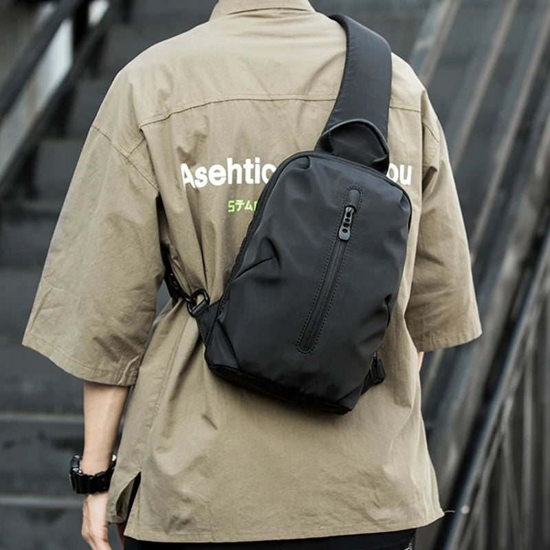 Person wearing a beige jacket with a black sling bag on a blurred background