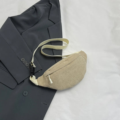 Beige waist bag on a dark gray suit jacket with a white background