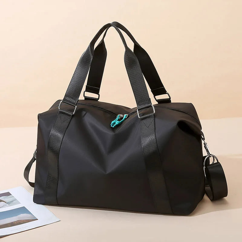 Black duffel bag with a strap on a beige background