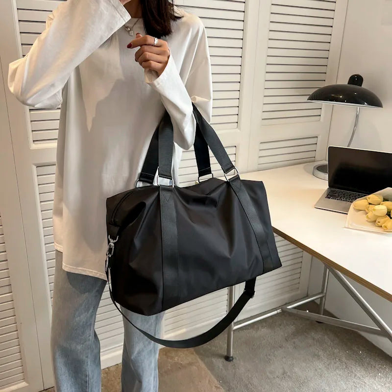Person holding a black bag in an indoor setting with a desk and lamp in the background.