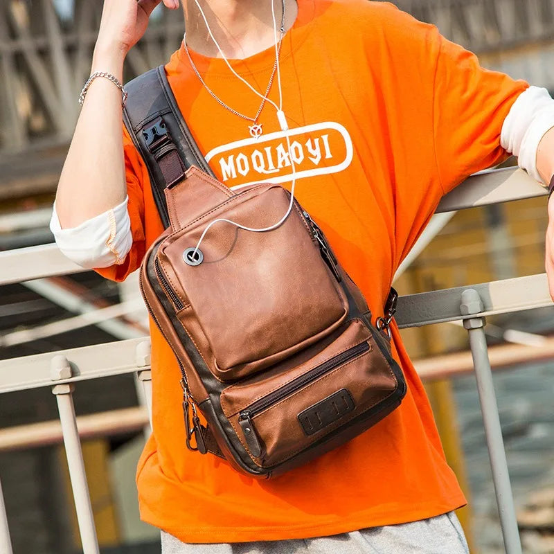Person wearing an orange shirt with a brand logo and carrying a brown sling bag.