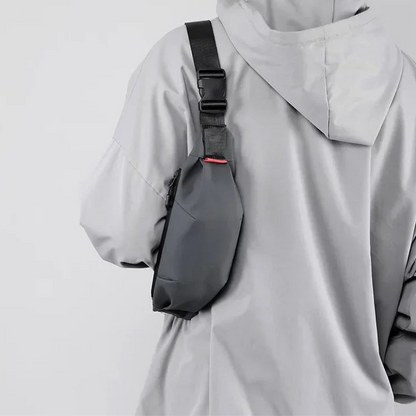 Person wearing a gray raincoat with a black backpack on a plain background