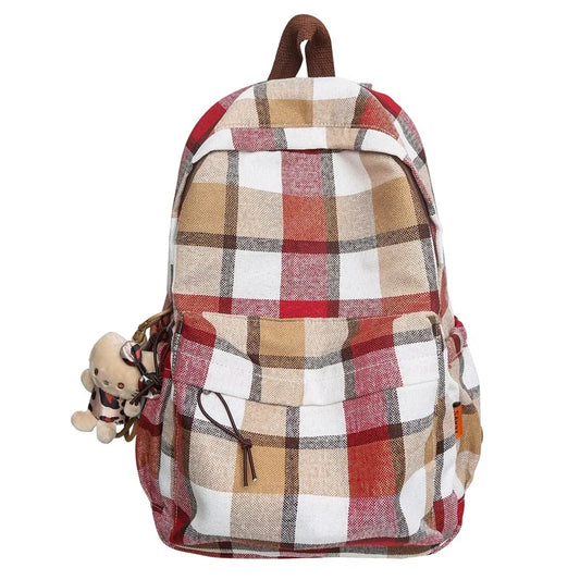 Plaid patterned backpack with a small plush toy attached on a white background