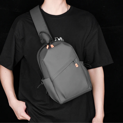 Person wearing a black t-shirt and a gray backpack against a black background