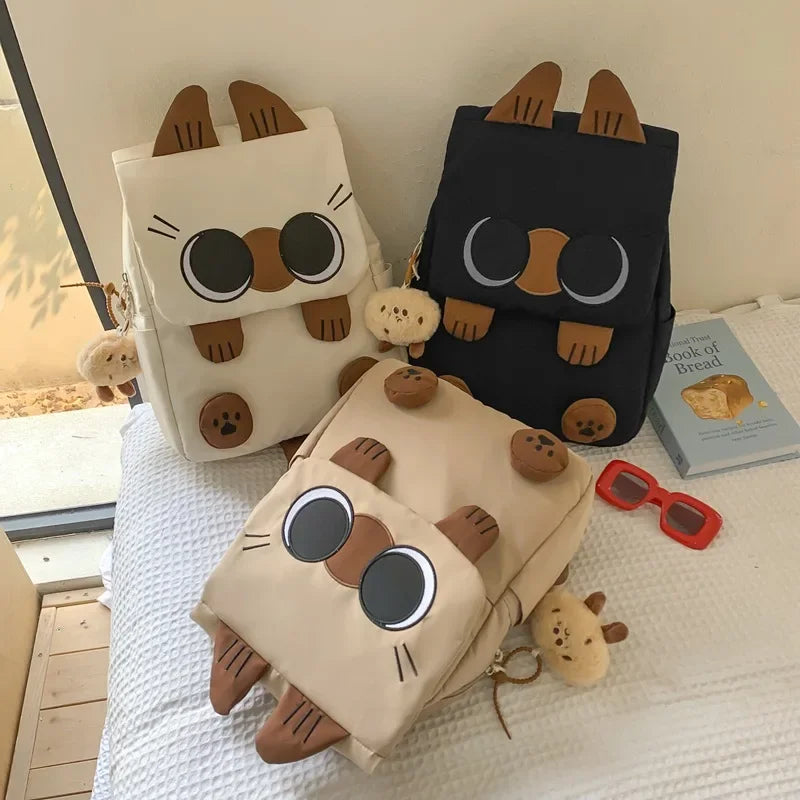 Three cat-shaped bags with ears and round eyes on a white surface.
