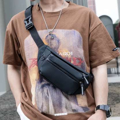 Person wearing a brown t-shirt with a graphic design and carrying a black crossbody bag.