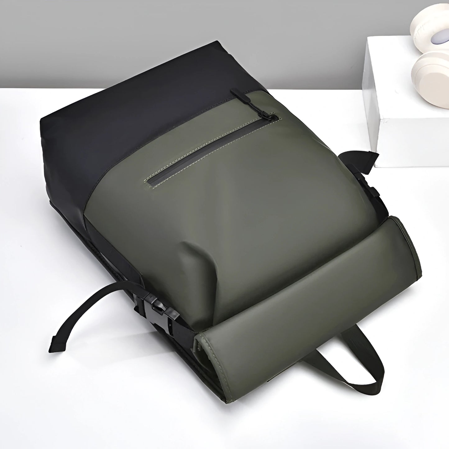 Green backpack on a white surface with a gray background