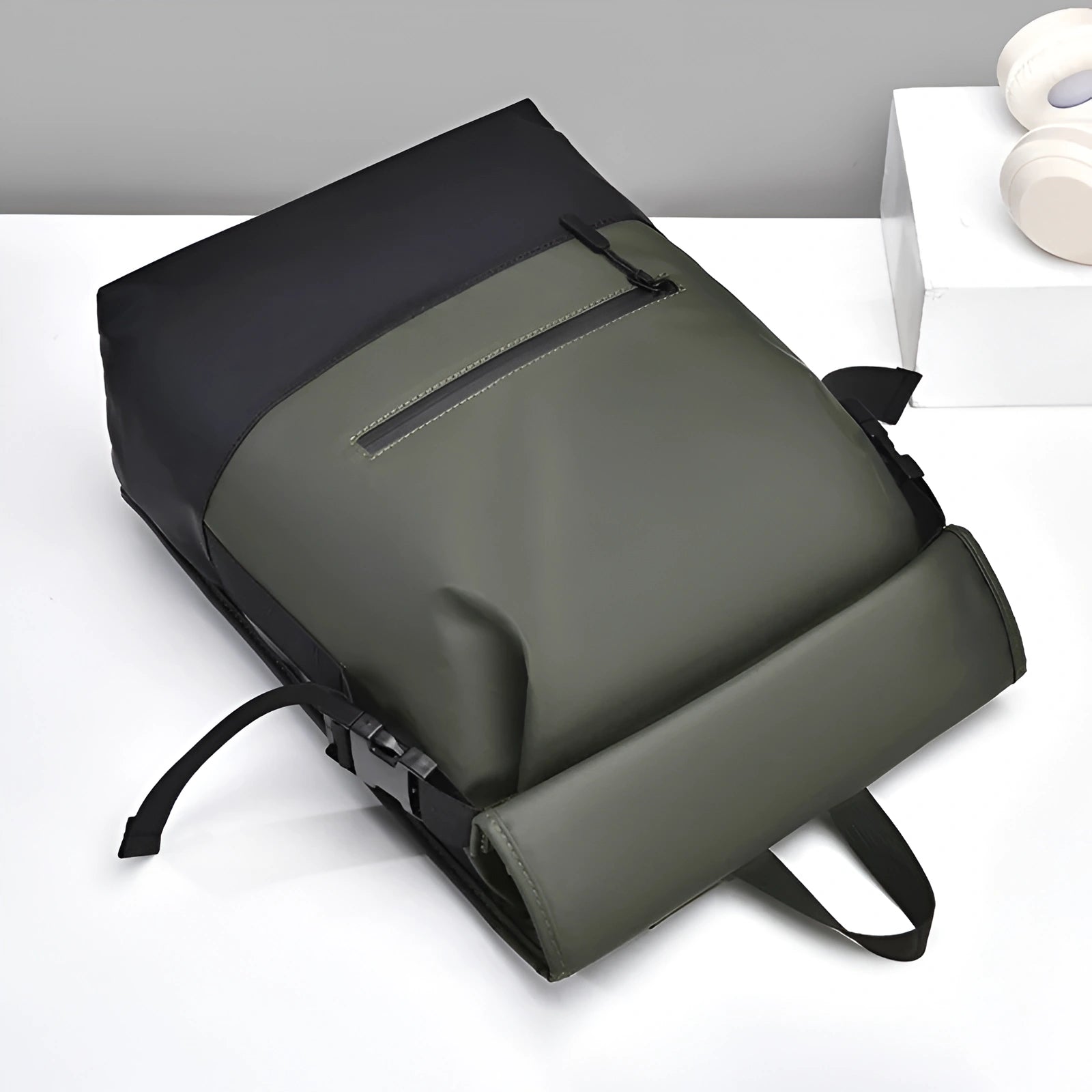 Green backpack on a white surface with a gray background