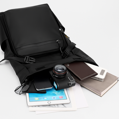 Black backpack with electronic devices and items on a white surface