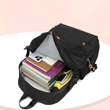 Black backpack with items like a phone, books, and sunglasses on a light pink background