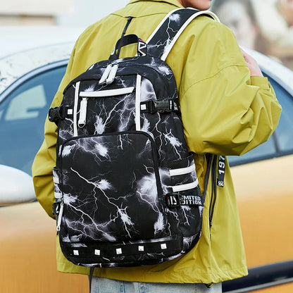 Person wearing a black backpack with white lightning patterns, standing outdoors.