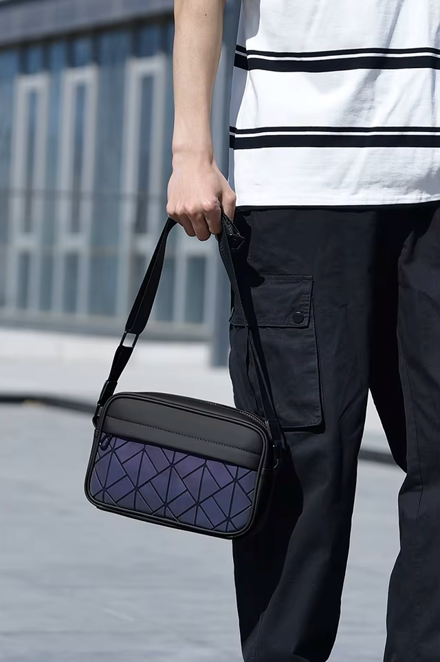 Person holding a black and purple geometric-patterned bag outdoors.