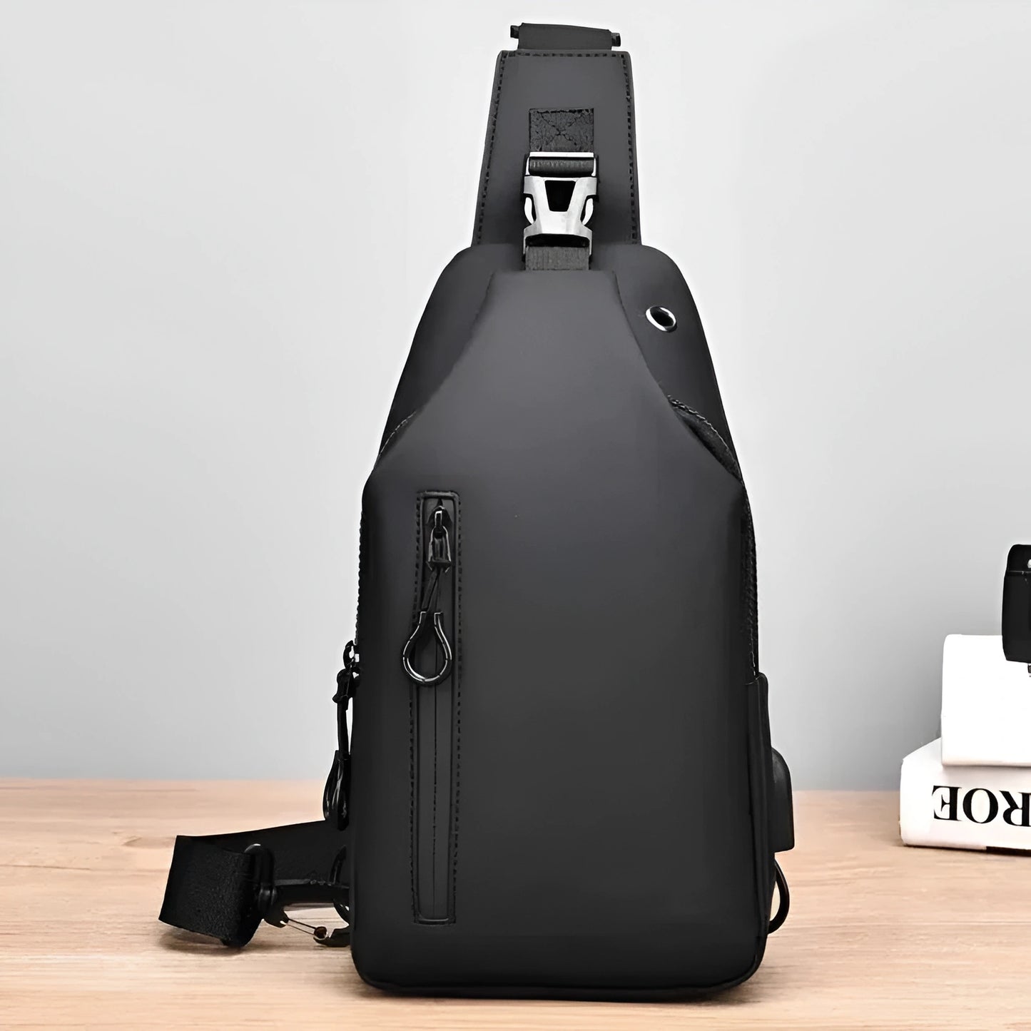 Black sling bag on a wooden surface with a light gray background