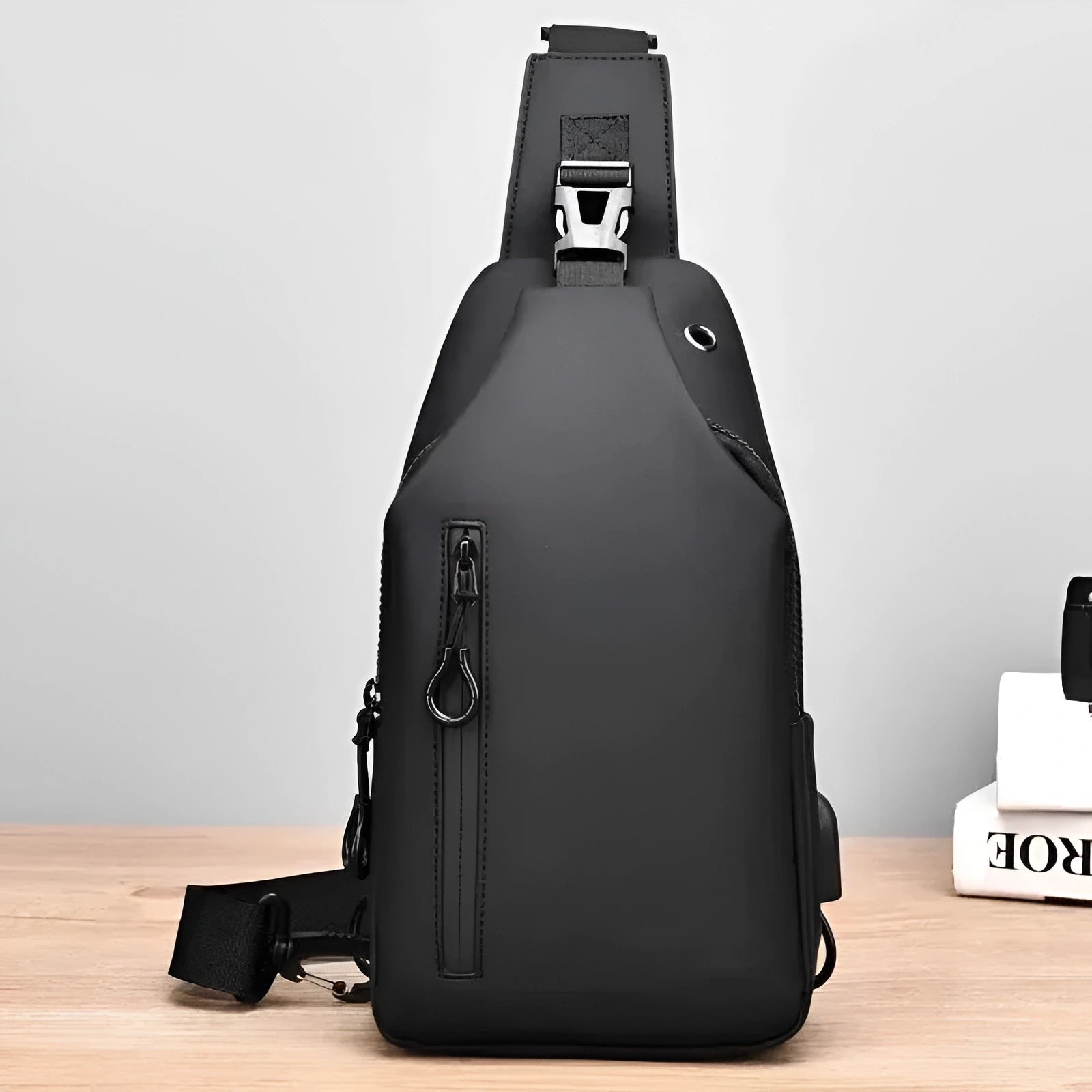 Black sling bag on a wooden surface with a light gray background