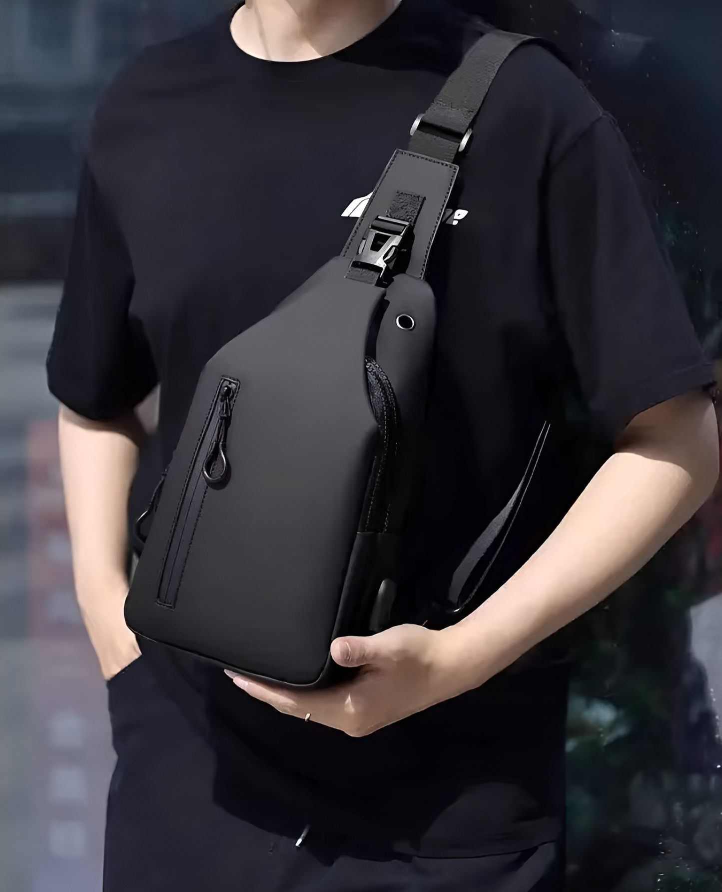 Person holding a black sling bag against a blurred background