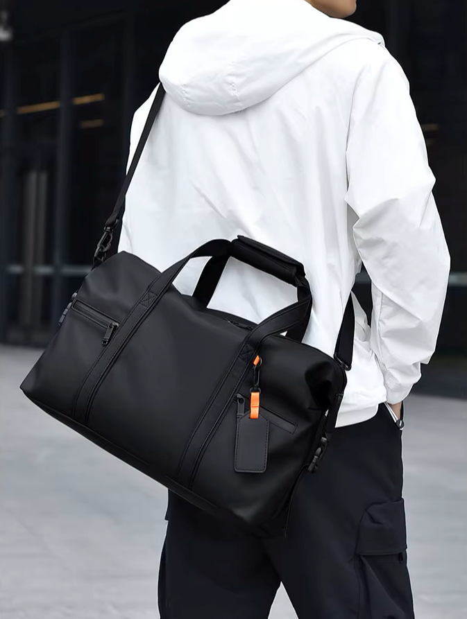 Person wearing a black duffel bag over one shoulder in an urban setting