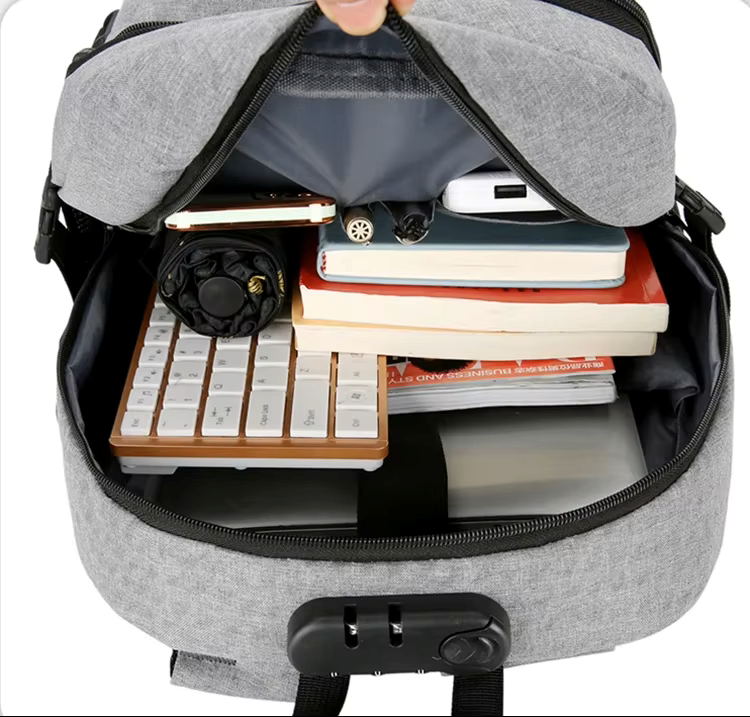 Gray backpack with items like a keyboard, books, and a phone inside