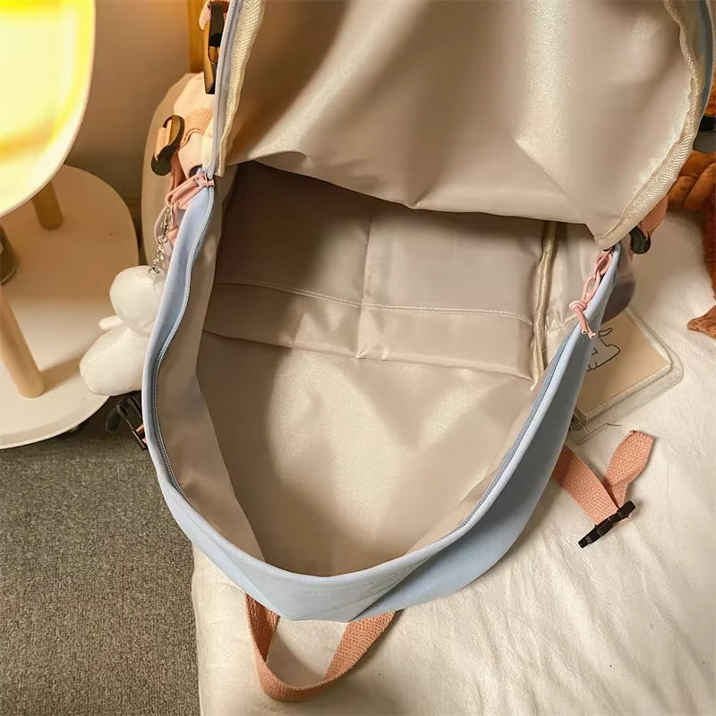 Beige backpack with a blue strap on a light-colored surface