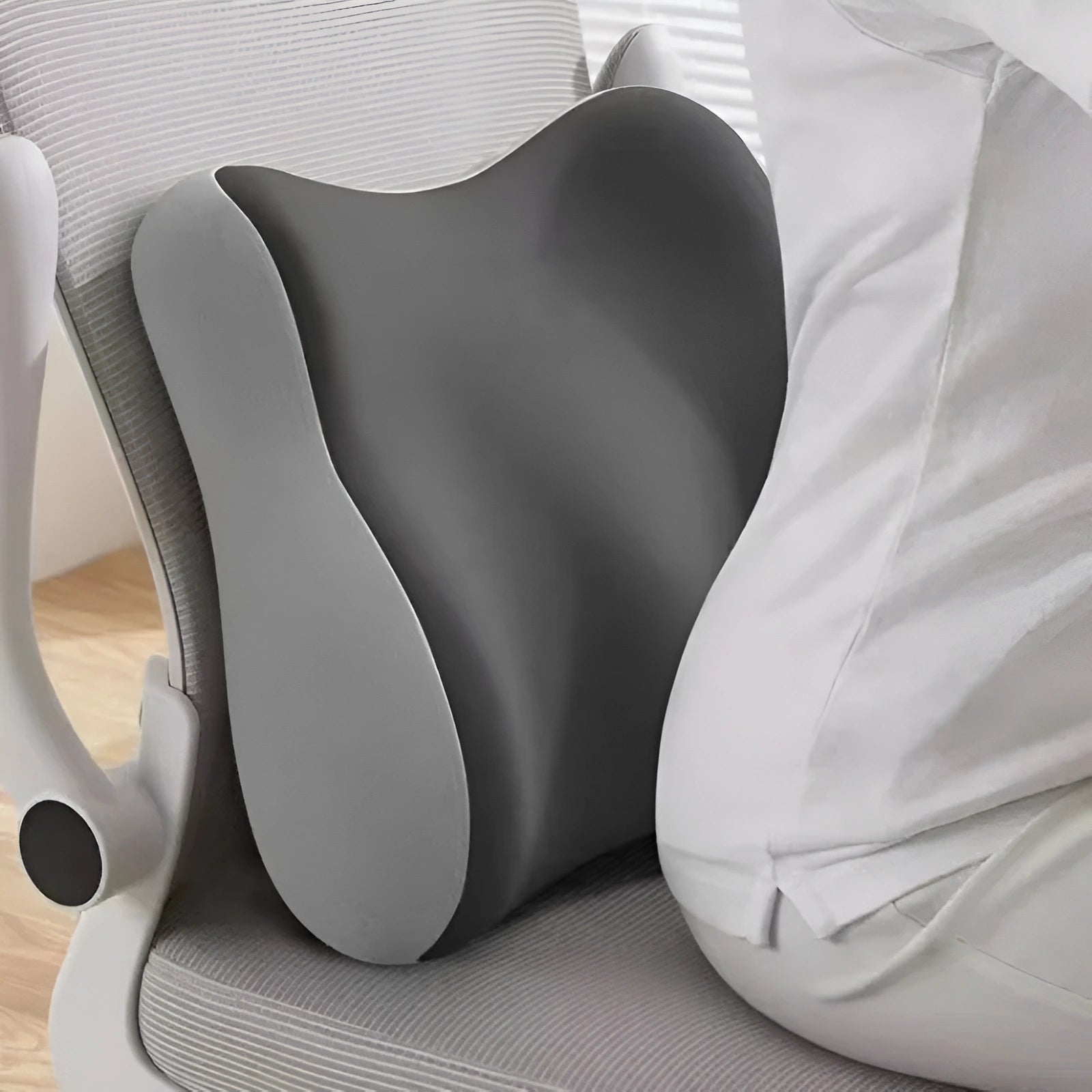 Gray ergonomic pillow on a chair with a person sitting back