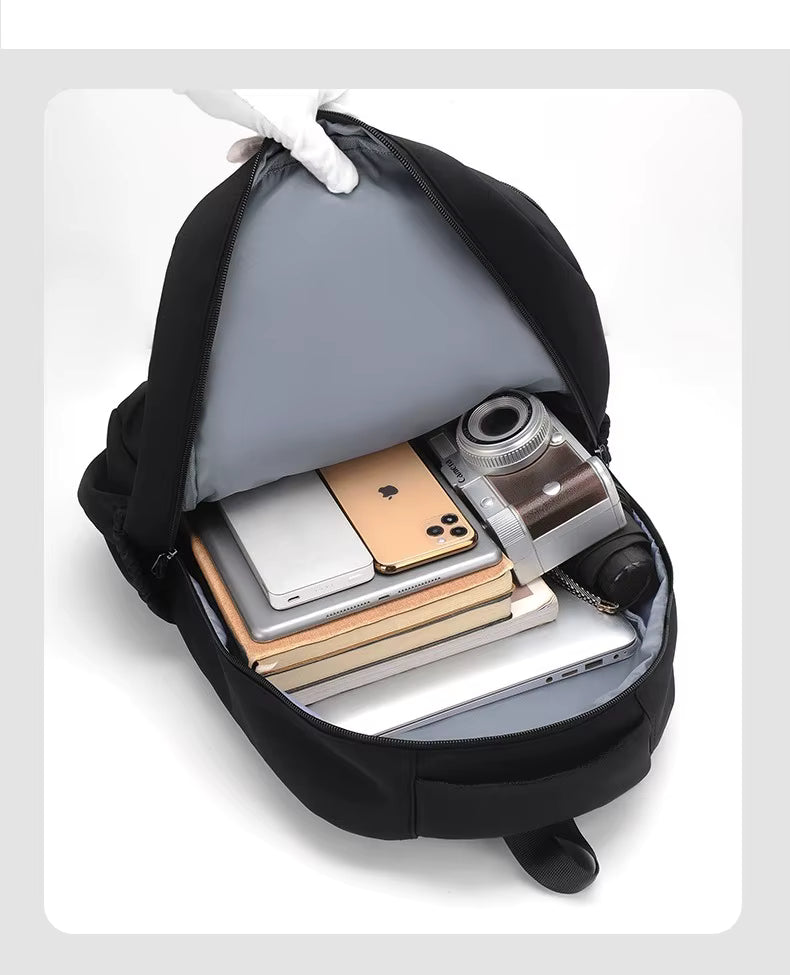 Black backpack with items including a phone, tablet, and camera.